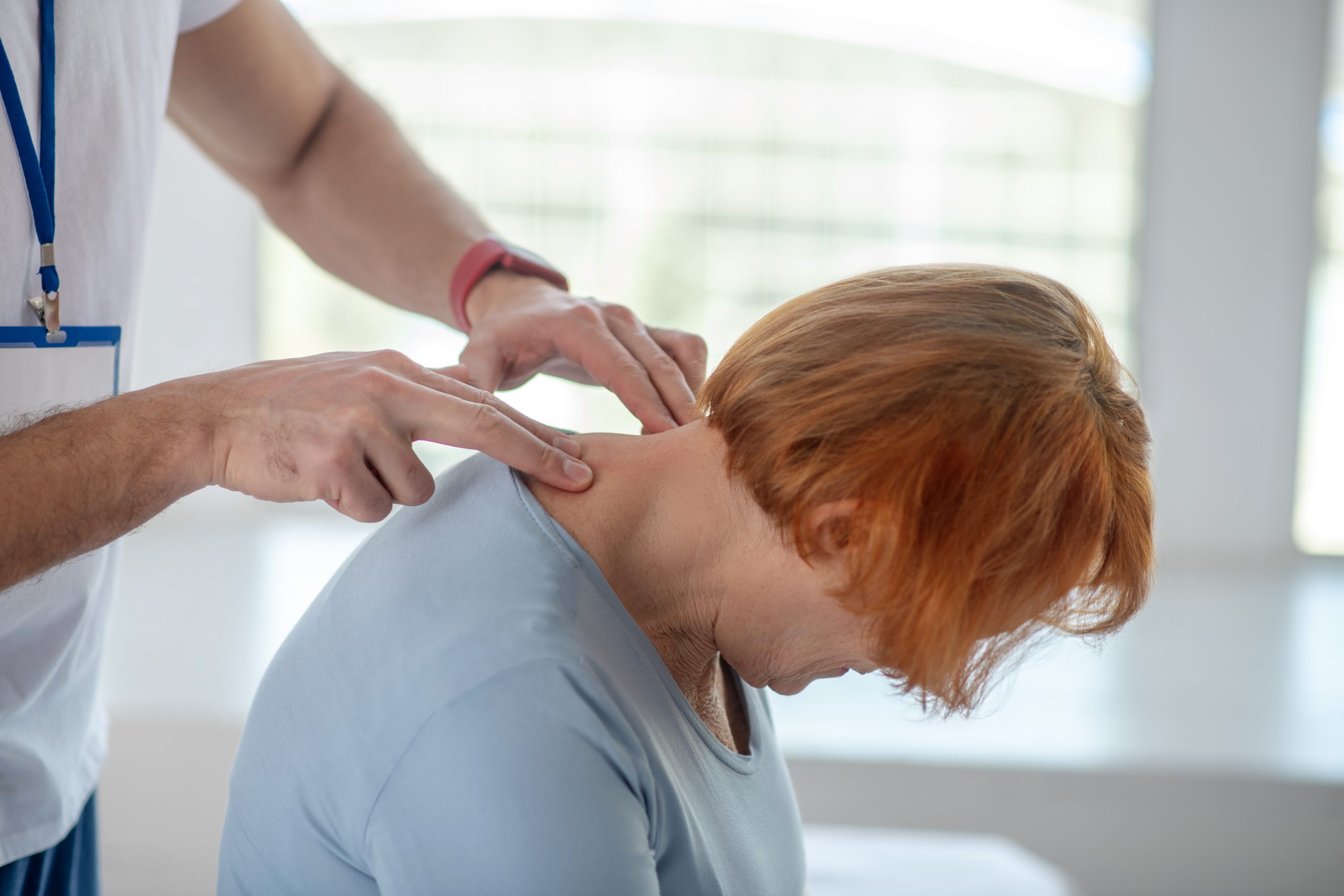 Medical procedure. Nice senior patient leaning her head forward while undergoing a medical procedure